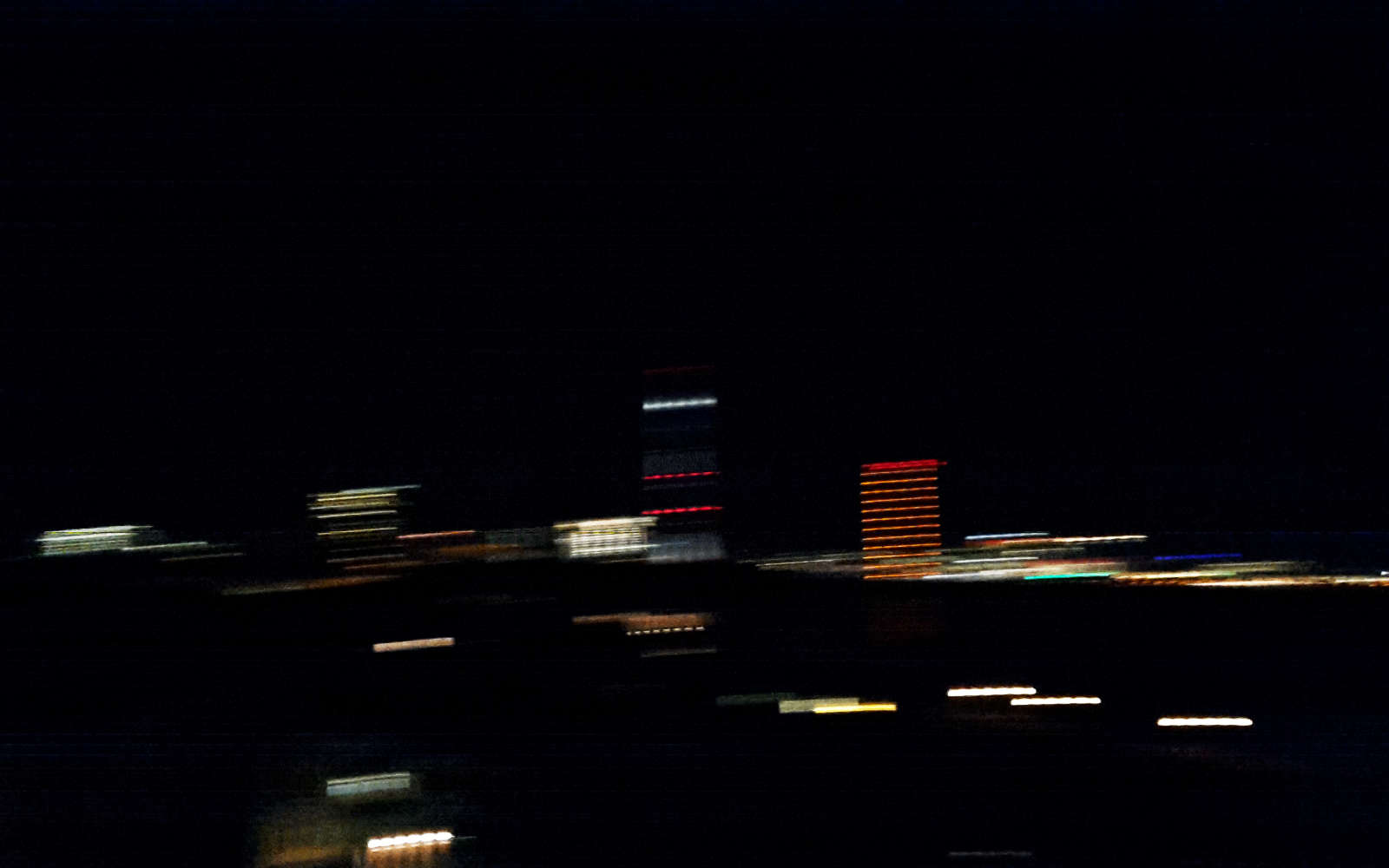 blurred photograph of düsseldorf skyline at night showing the lights of the bridges crossing the river rhine